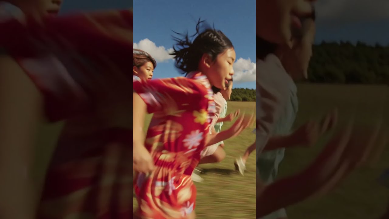 A vibrant, candid shot of happy East Asian kids actively playing and running in a sunny grassy fi...